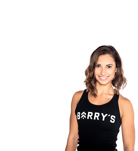 Barry’s instructor wearing a black top standing confidently smiling against a white background