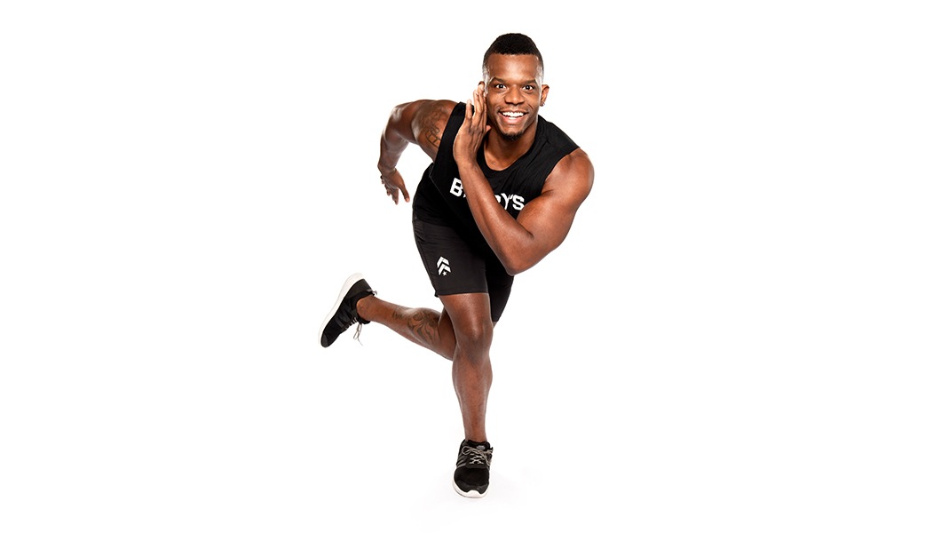 Barry's instructor in lunge, wearing a black tank top against a white background, ready for the next workout challenge.