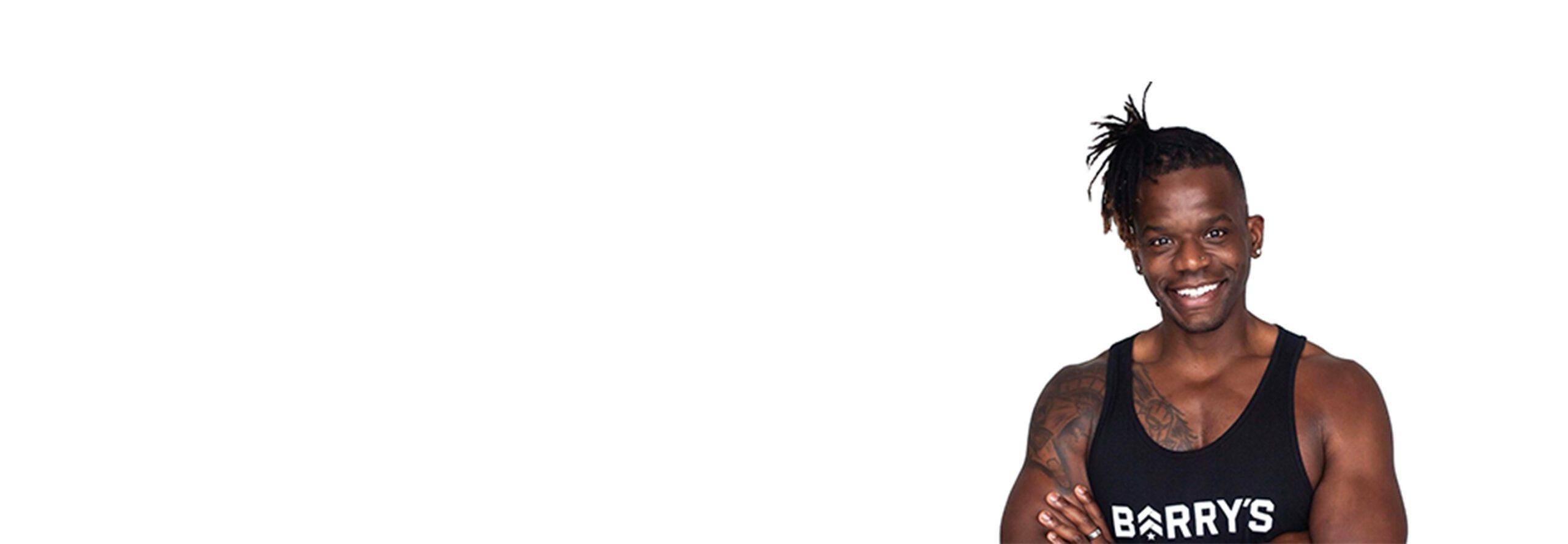 Barry's instructor standing confidently with arms crossed in front, wearing a black tank top against a white background, ready for the next workout challenge.