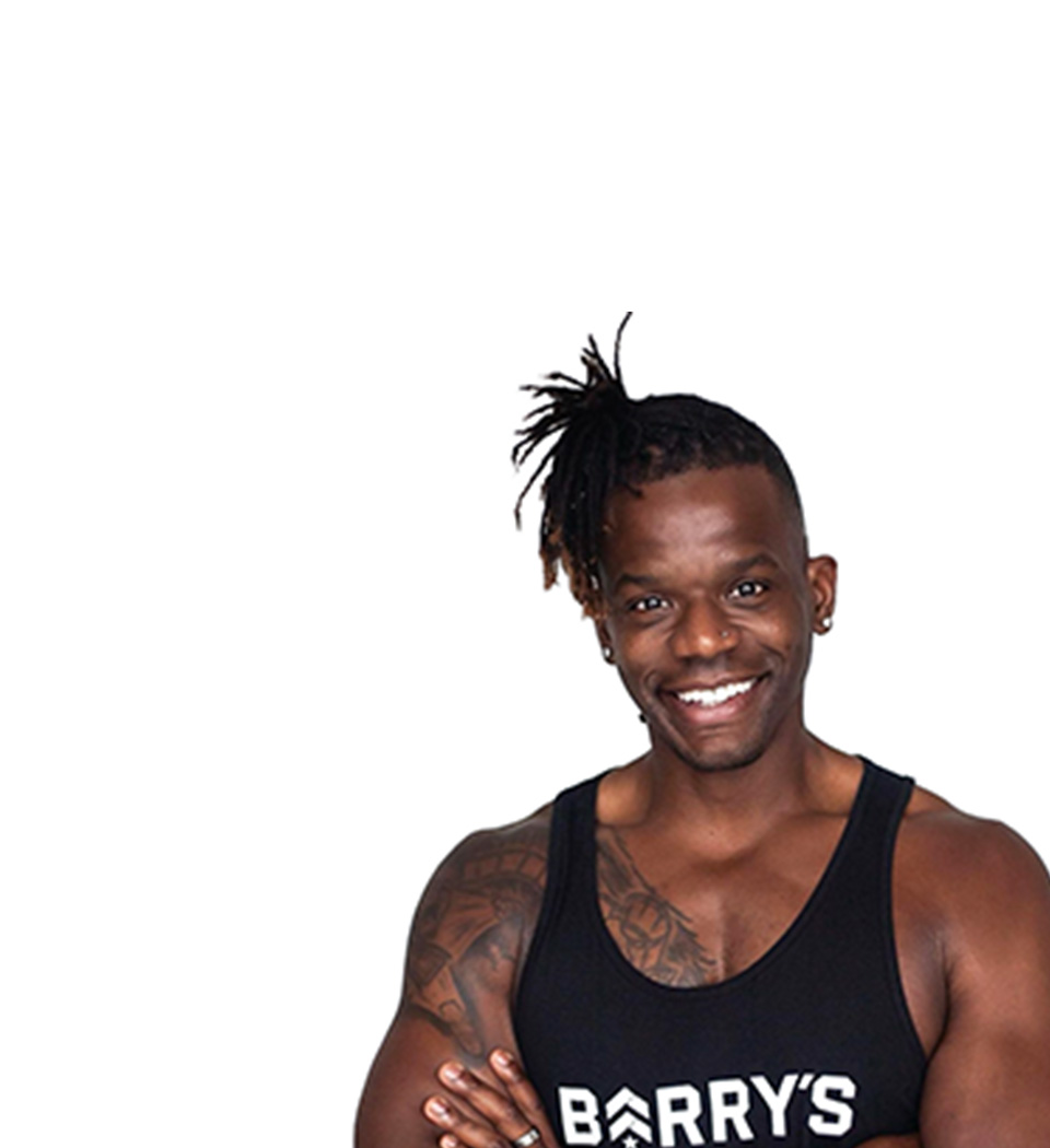 Barry's instructor standing confidently with arms crossed in front, wearing a black tank top against a white background, ready for the next workout challenge.