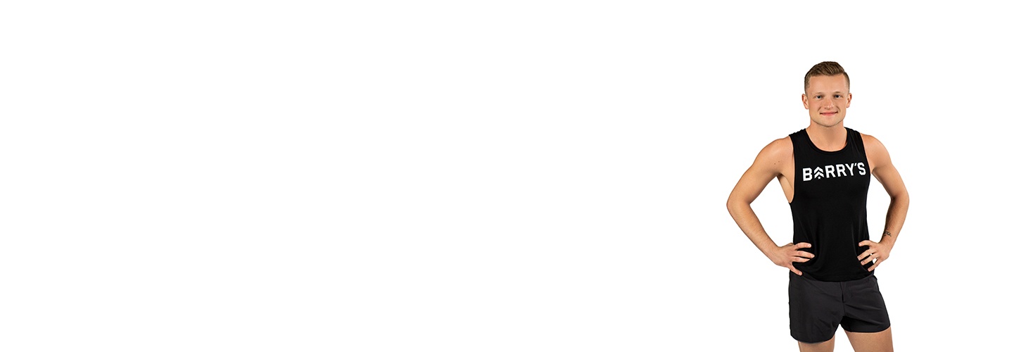 Barry’s instructor wearing a black top standing confidently smiling against a white background