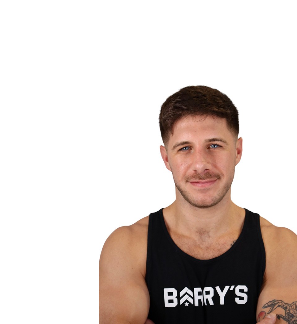 Barry’s instructor wearing a black top standing confidently smiling against a white background