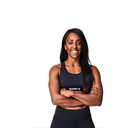 Barry’s instructor wearing a black top standing confidently smiling against a white background