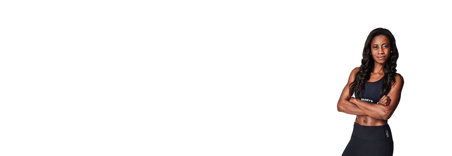 Barry’s instructor wearing a black top standing confidently smiling against a white background