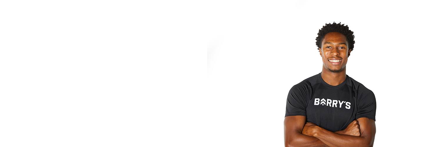 Barry’s instructor wearing a black top standing confidently smiling against a white background