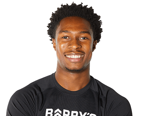 Barry’s instructor wearing a black top standing confidently smiling against a white background
