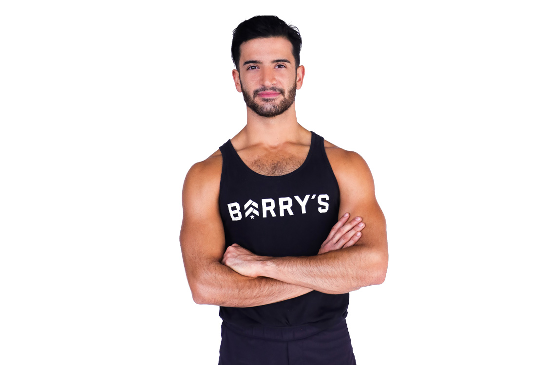 Barry’s instructor wearing a black top standing confidently smiling against a white background