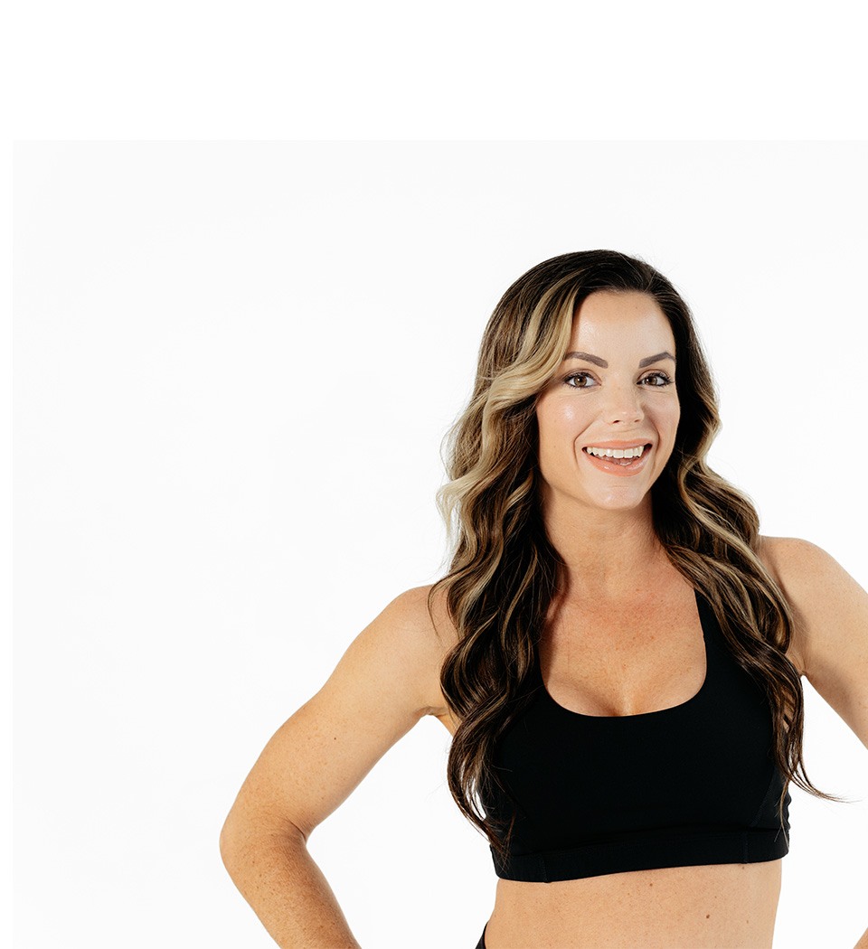 Barry’s instructor wearing a black top standing confidently smiling against a white background