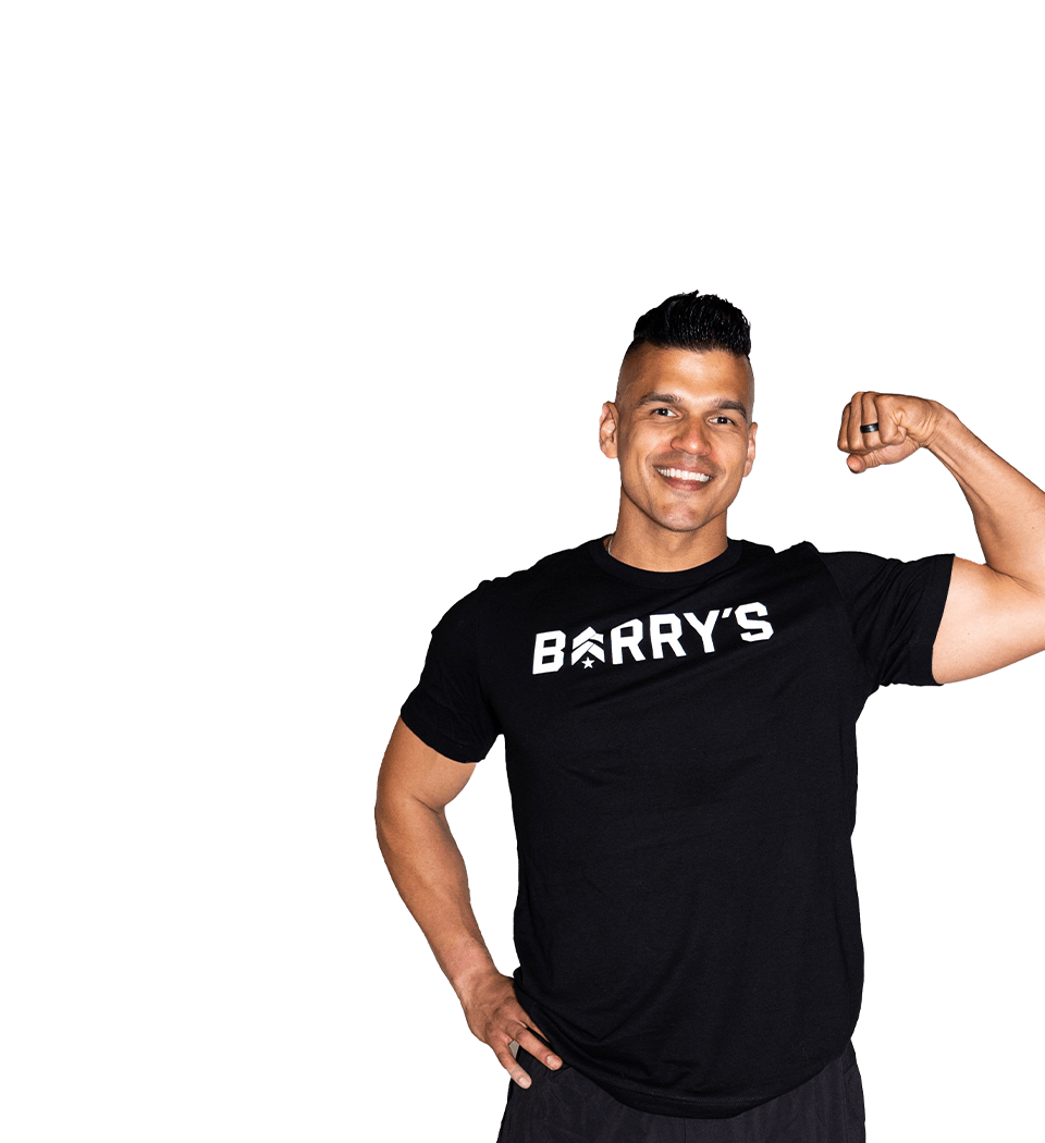 Barry’s instructor wearing a black top standing confidently smiling against a white background