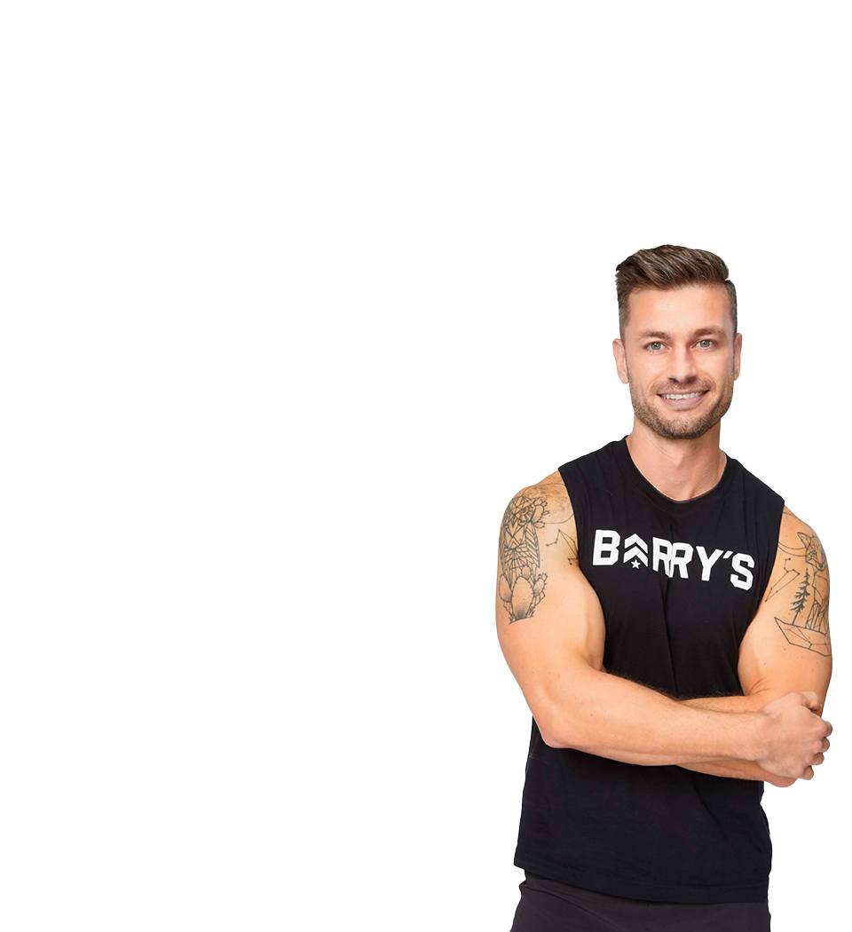Barry's instructor standing confidently with arms crossed, wearing a black tank top against a white background, ready for the next workout challenge.