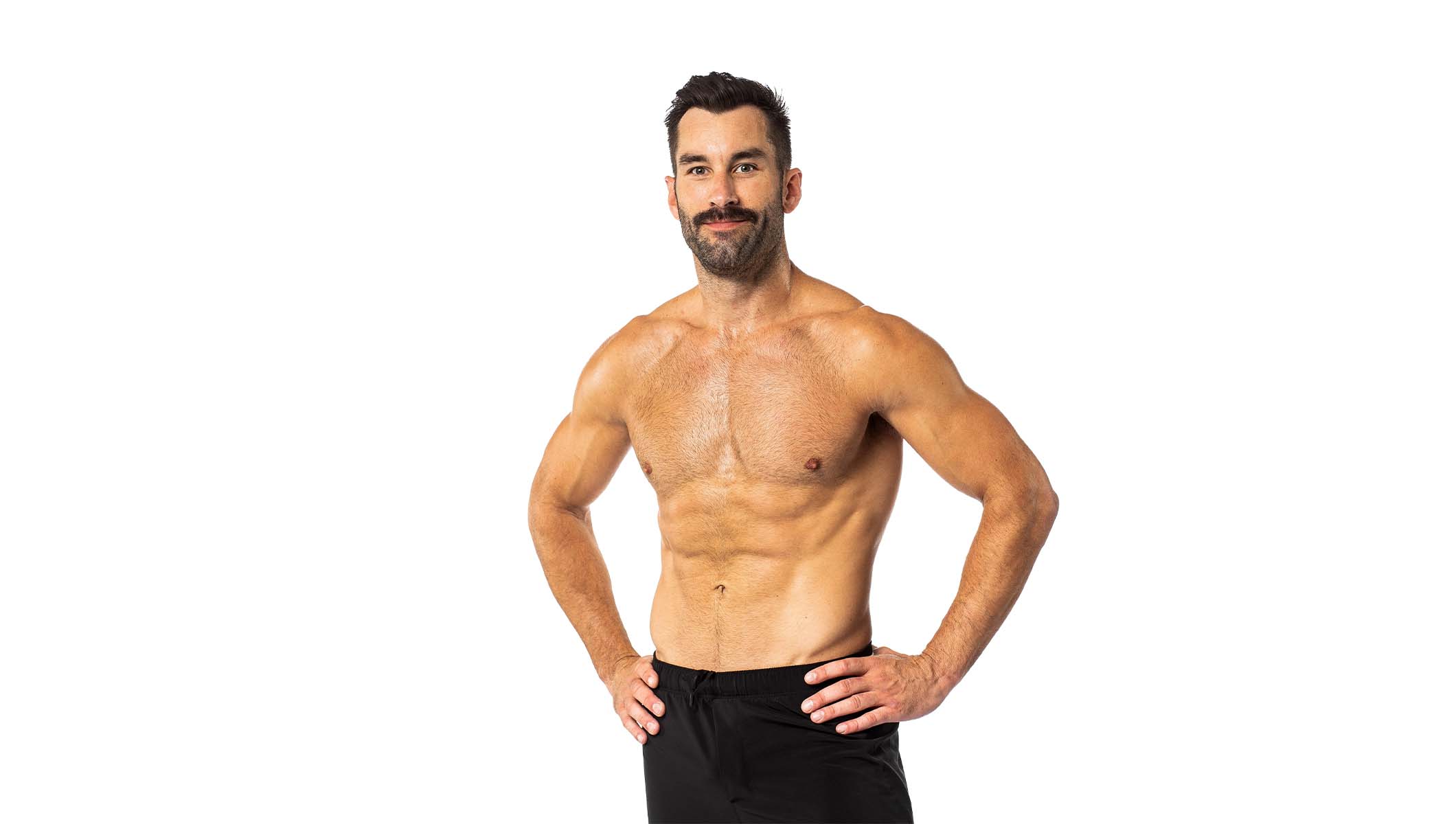 Barry’s instructor shirtless with hands on hips standing confidently smiling against a white background