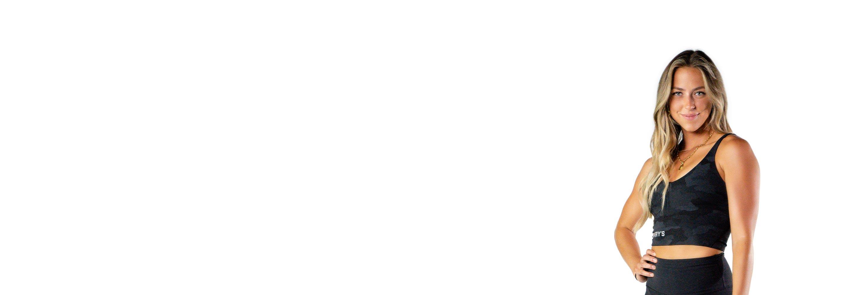 Barry’s instructor wearing a black top standing confidently smiling against a white background