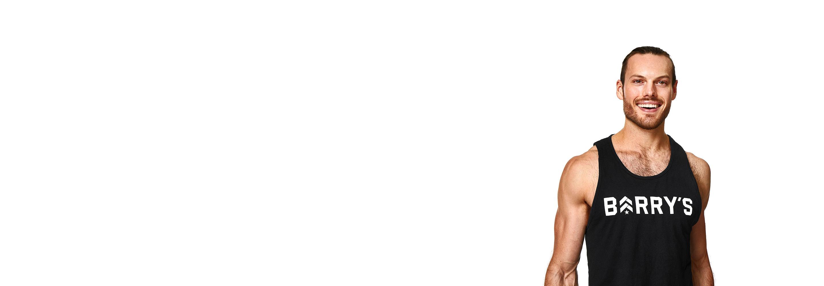 Barry’s instructor wearing a black top standing confidently smiling against a white background