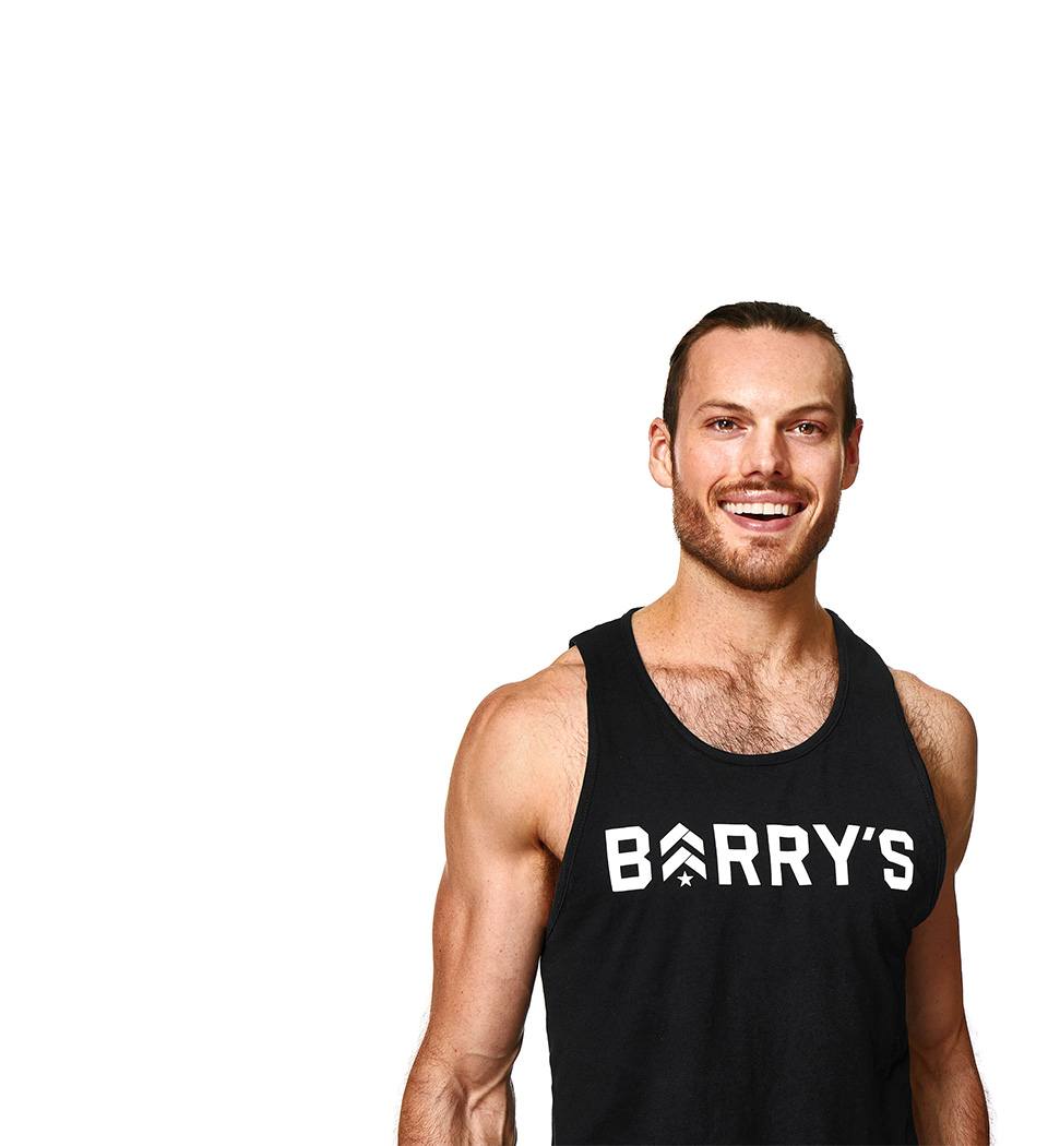 Barry’s instructor wearing a black top standing confidently smiling against a white background