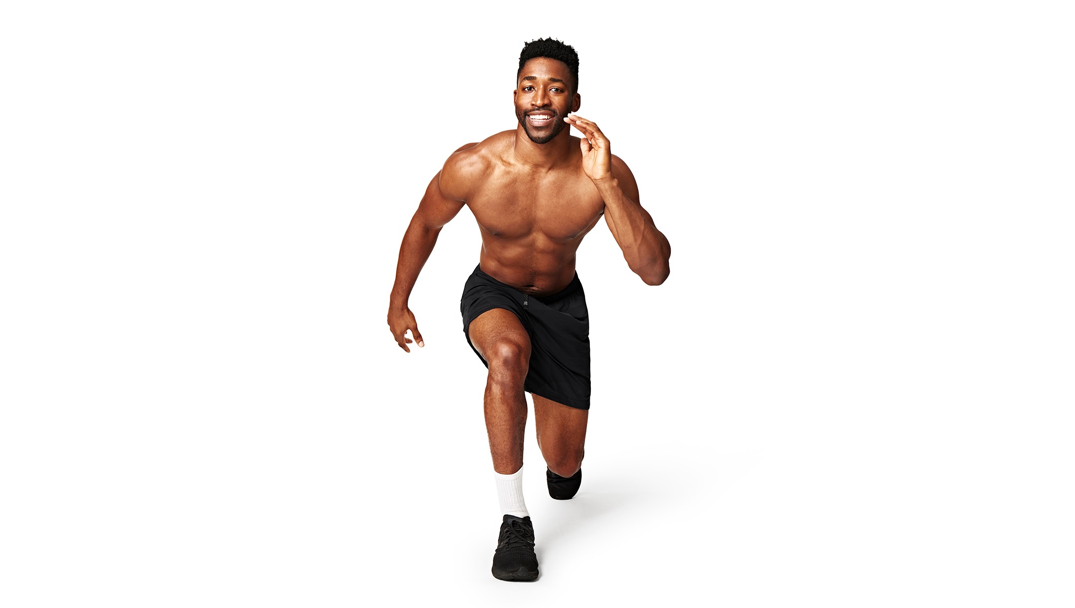 Barry’s instructor shirtless wearing black shorts in a lunge position smiling against a white background