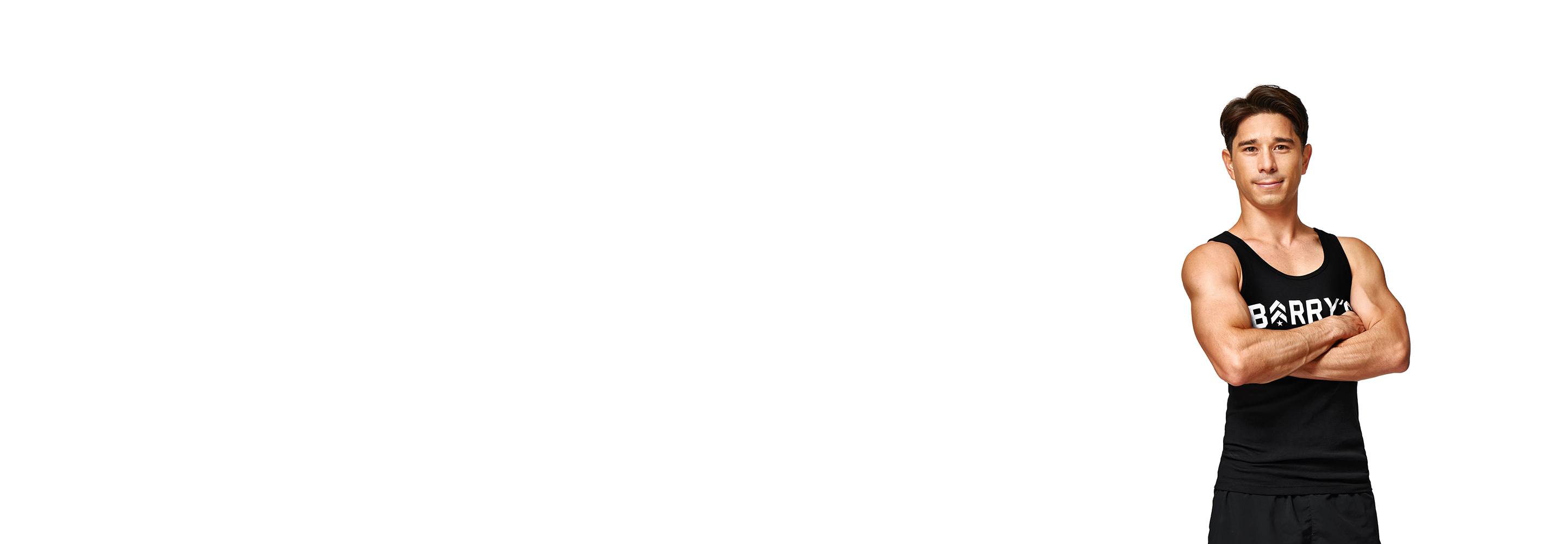 Barry’s instructor wearing a black top standing confidently smiling against a white background