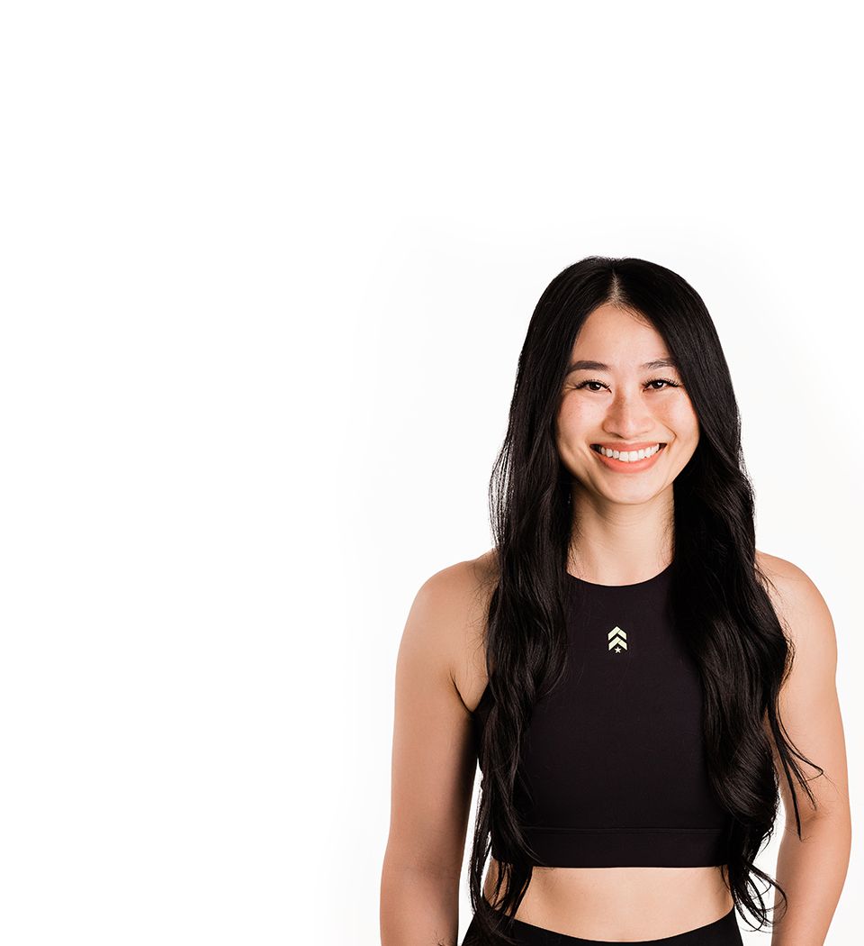 Barry’s instructor wearing a black top standing confidently smiling against a white background