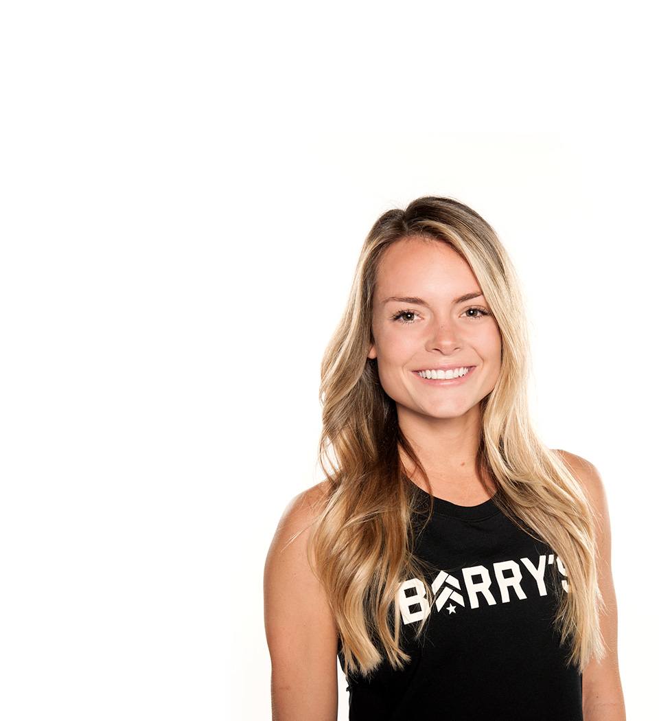 Barry’s instructor wearing a black top standing confidently smiling against a white background