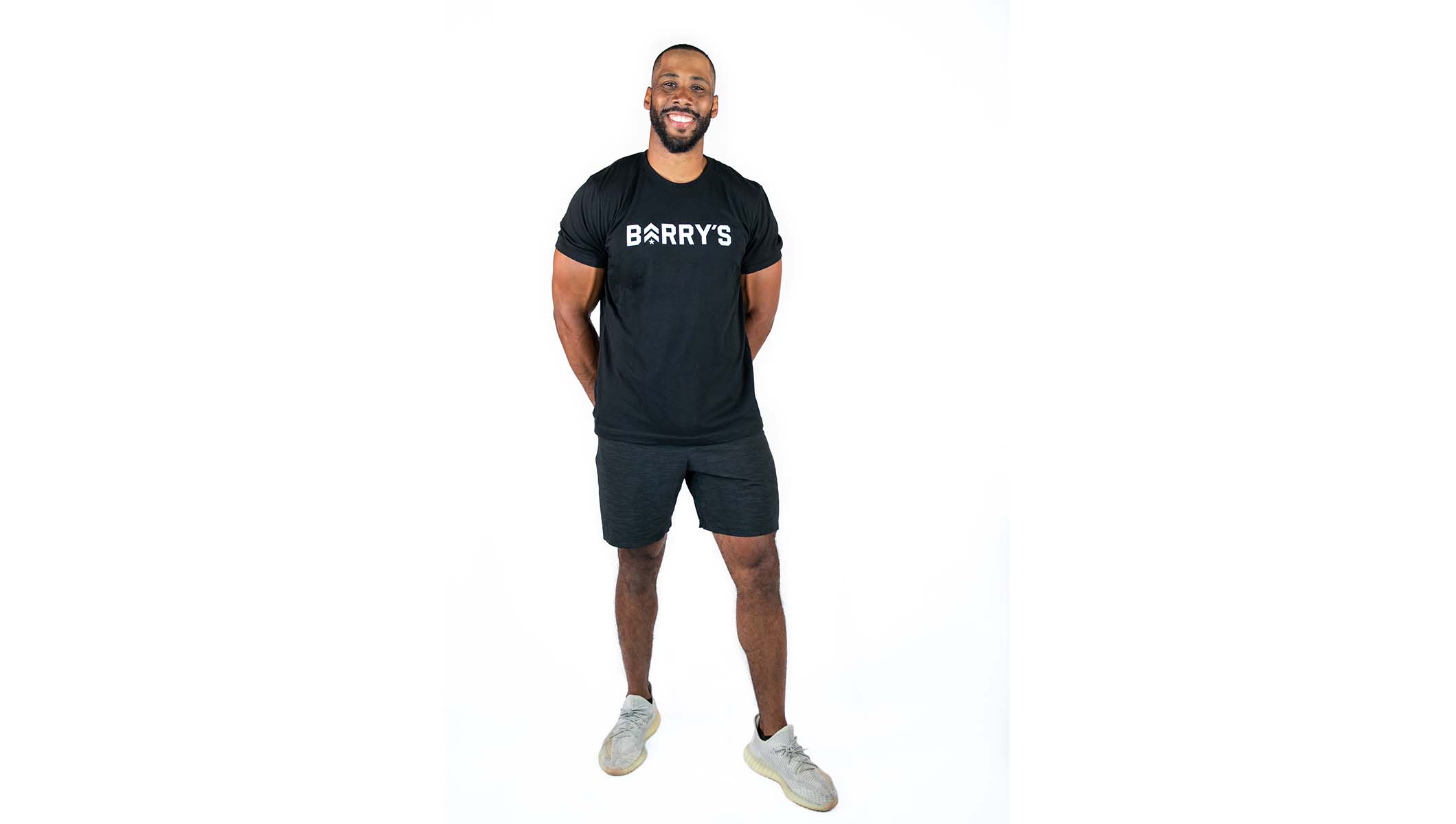 Corey Lemonier instructor standing confidently, wearing a black top against a white background, ready for the next workout challenge.