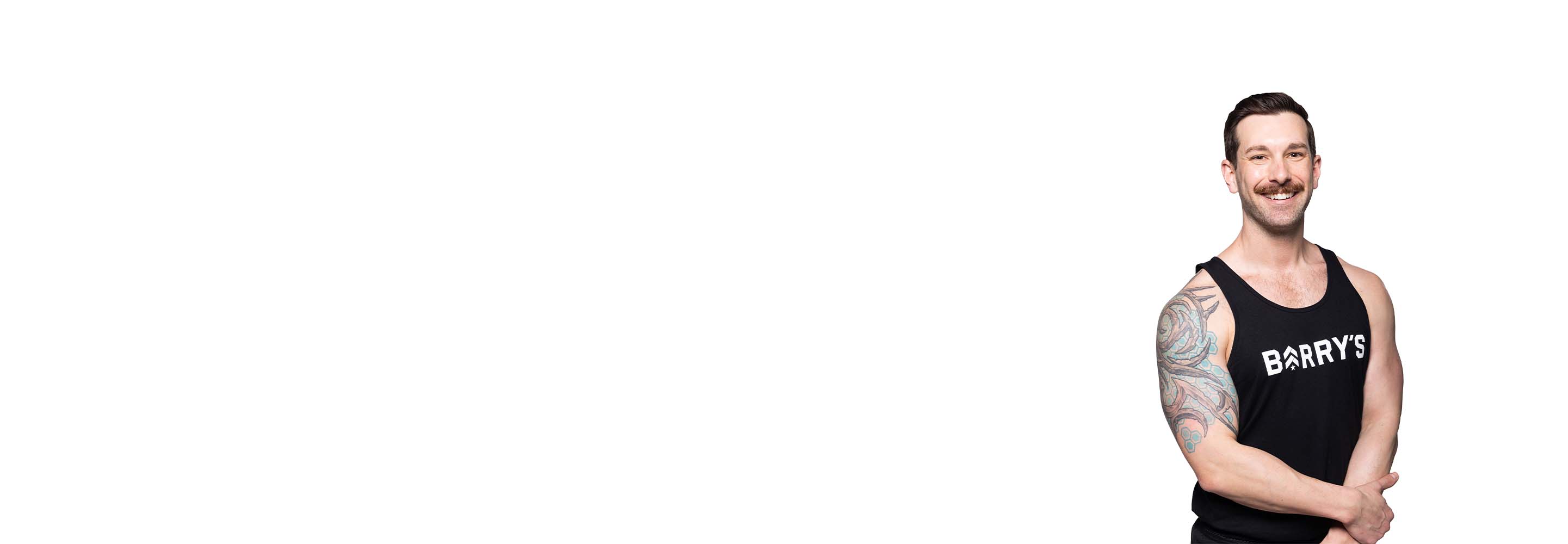 Barry’s instructor wearing a black top standing confidently smiling against a white background