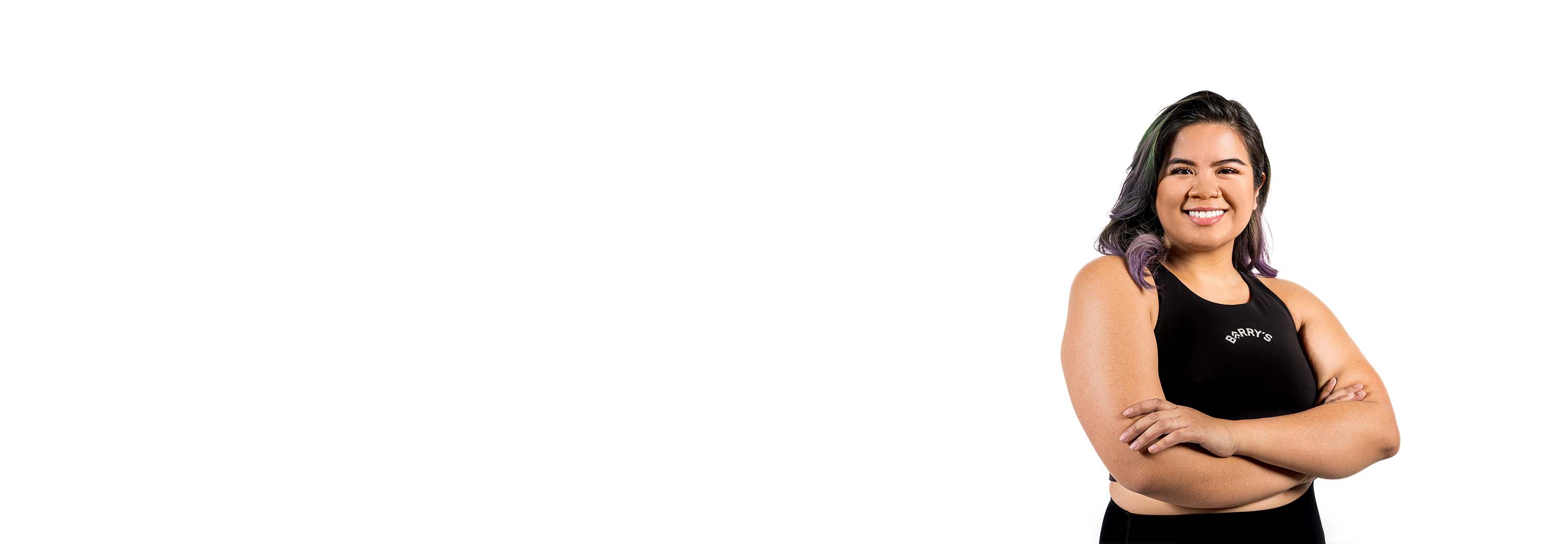 Barry’s instructor wearing a black top standing confidently smiling against a white background