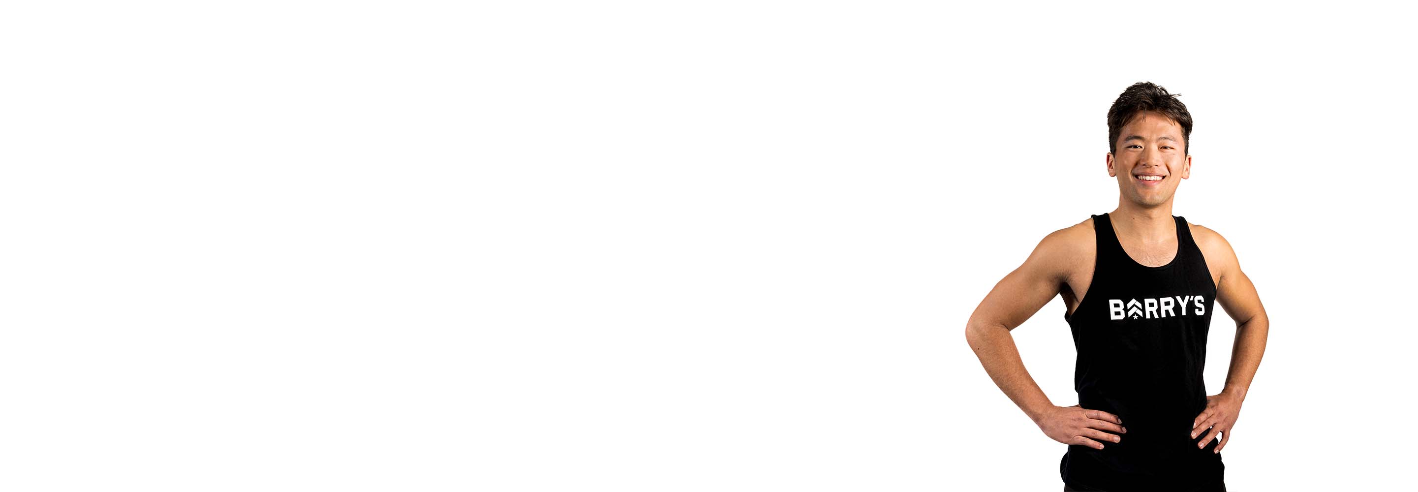 Barry’s instructor wearing a black top standing confidently smiling against a white background