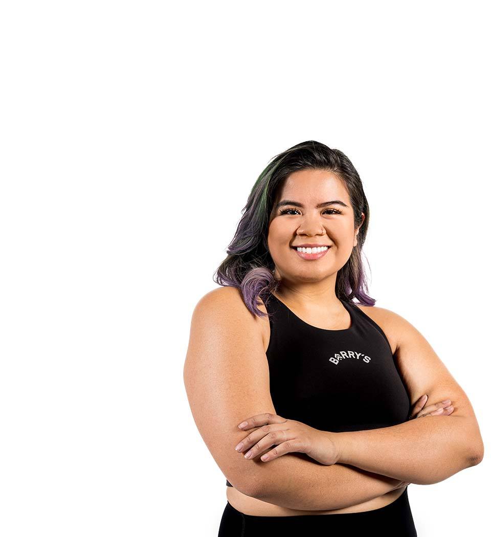 Barry’s instructor wearing a black top standing confidently smiling against a white background