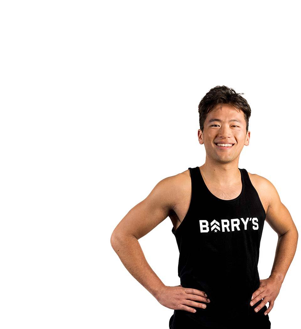 Barry’s instructor wearing a black top standing confidently smiling against a white background