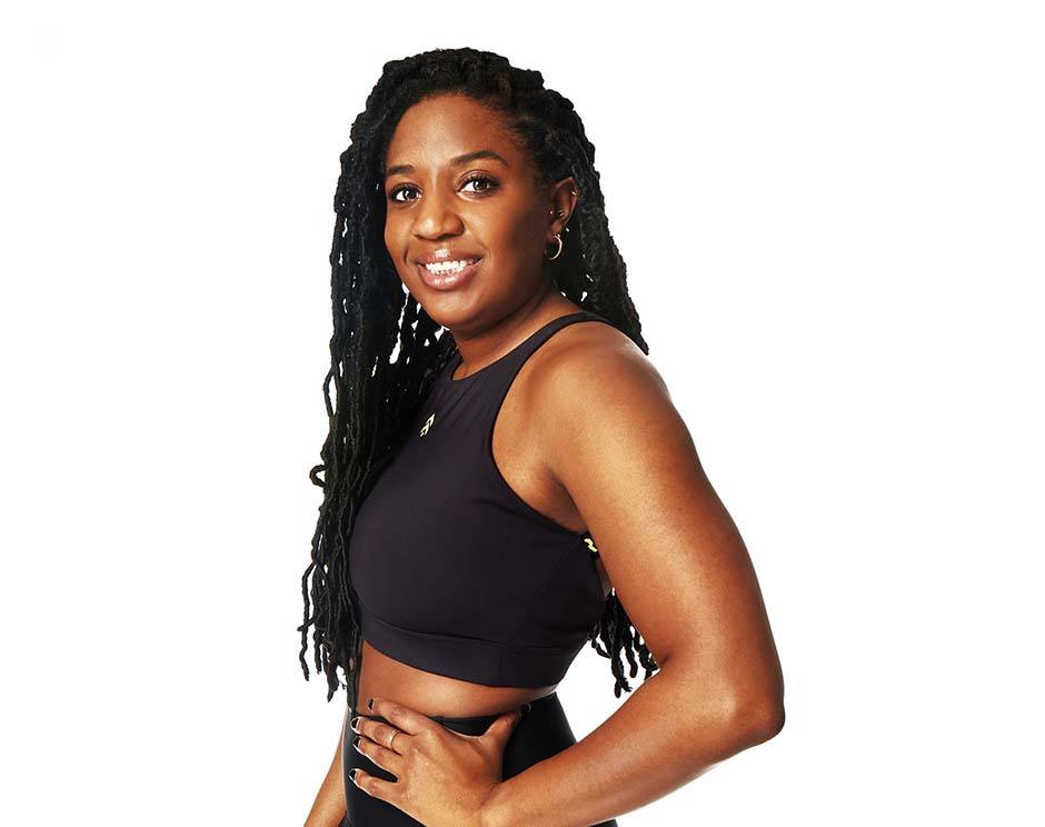 Barry’s instructor wearing a black top standing confidently smiling against a white background