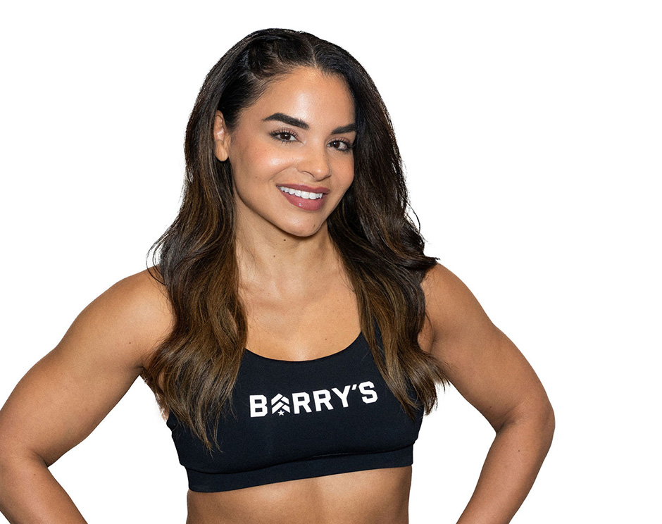 Barry’s instructor wearing a black top standing confidently smiling against a white background