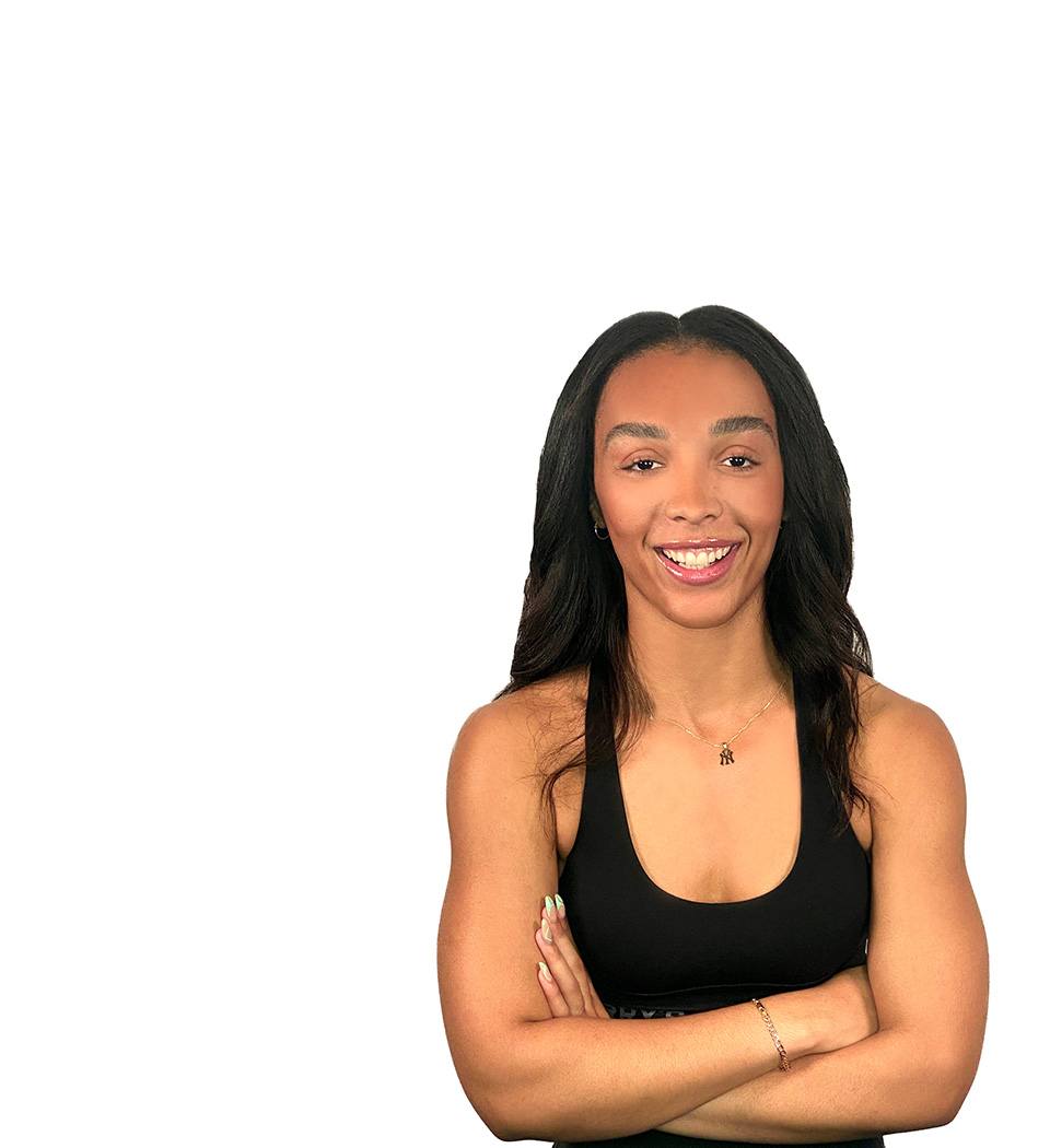 Barry’s instructor wearing a black top standing confidently smiling against a white background