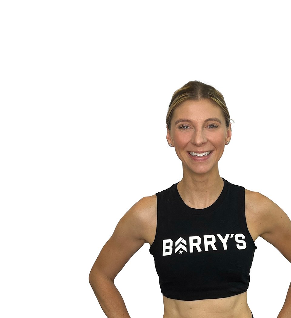 Barry’s instructor wearing a black top standing confidently smiling against a white background