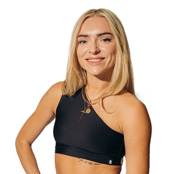 Barry’s instructor wearing a black top standing confidently smiling against a white background