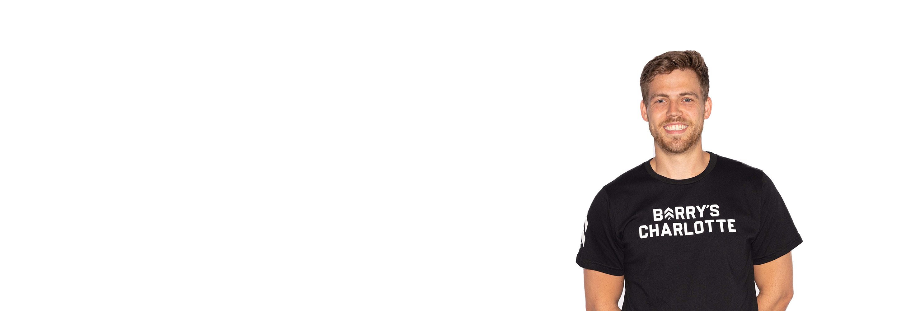 Barry’s instructor wearing a black top standing confidently smiling against a white background