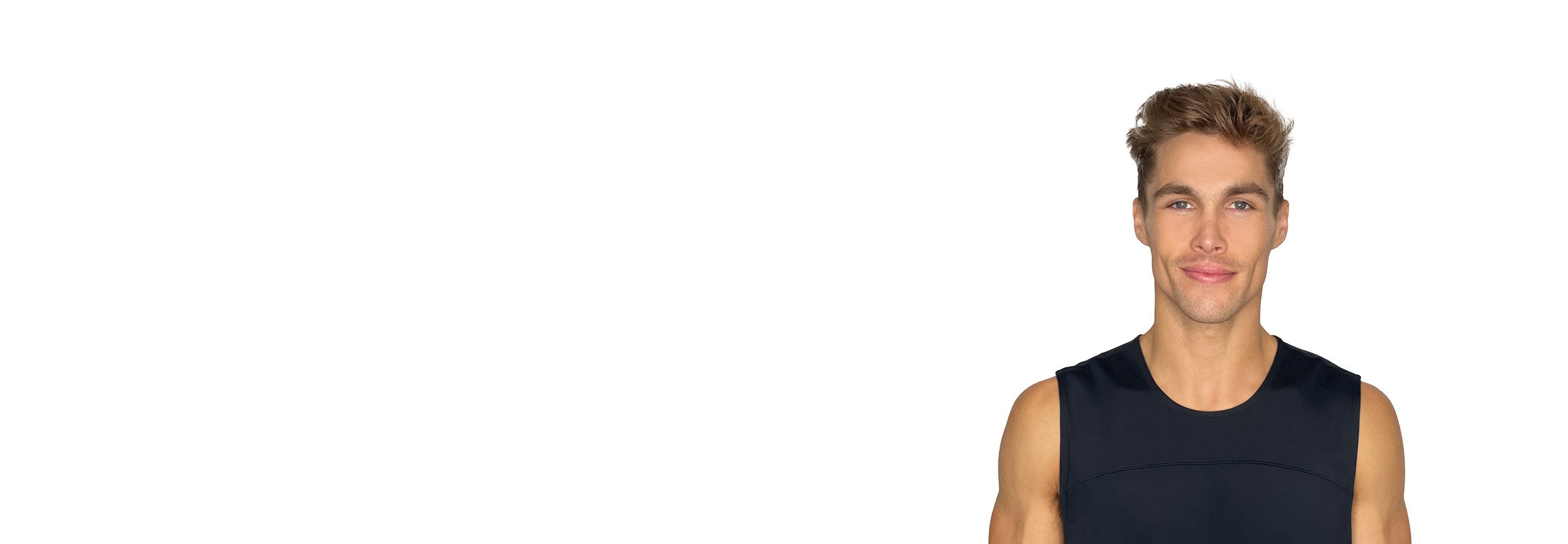 Barry's instructor standing confidently with arms by his side, wearing a black tank top against a white background, ready for the next workout challenge.