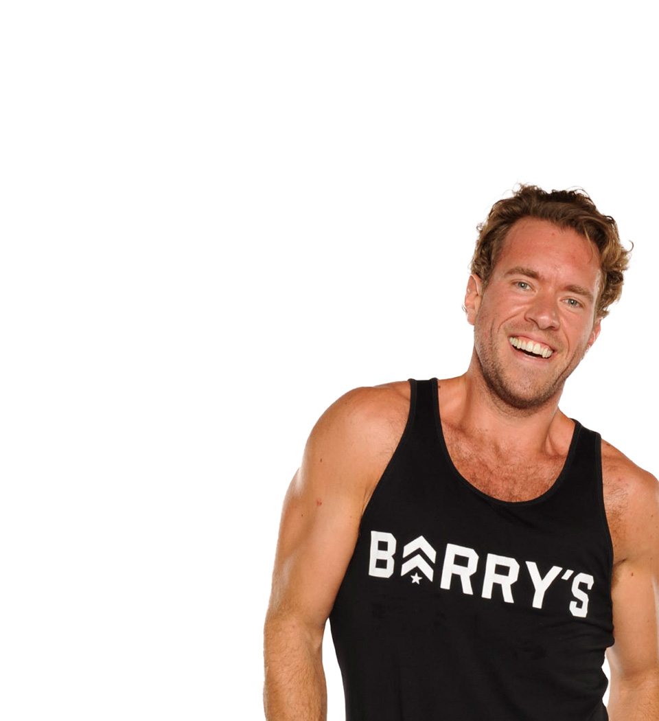 Barry’s instructor wearing a black top standing confidently smiling against a white background