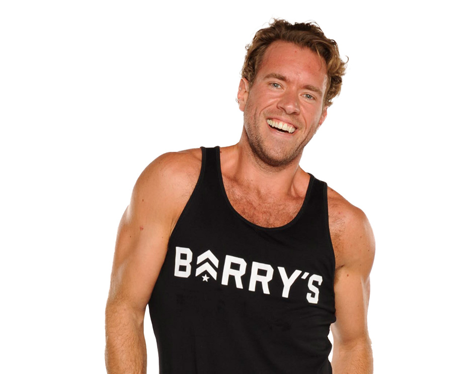 Barry’s instructor wearing a black top standing confidently smiling against a white background