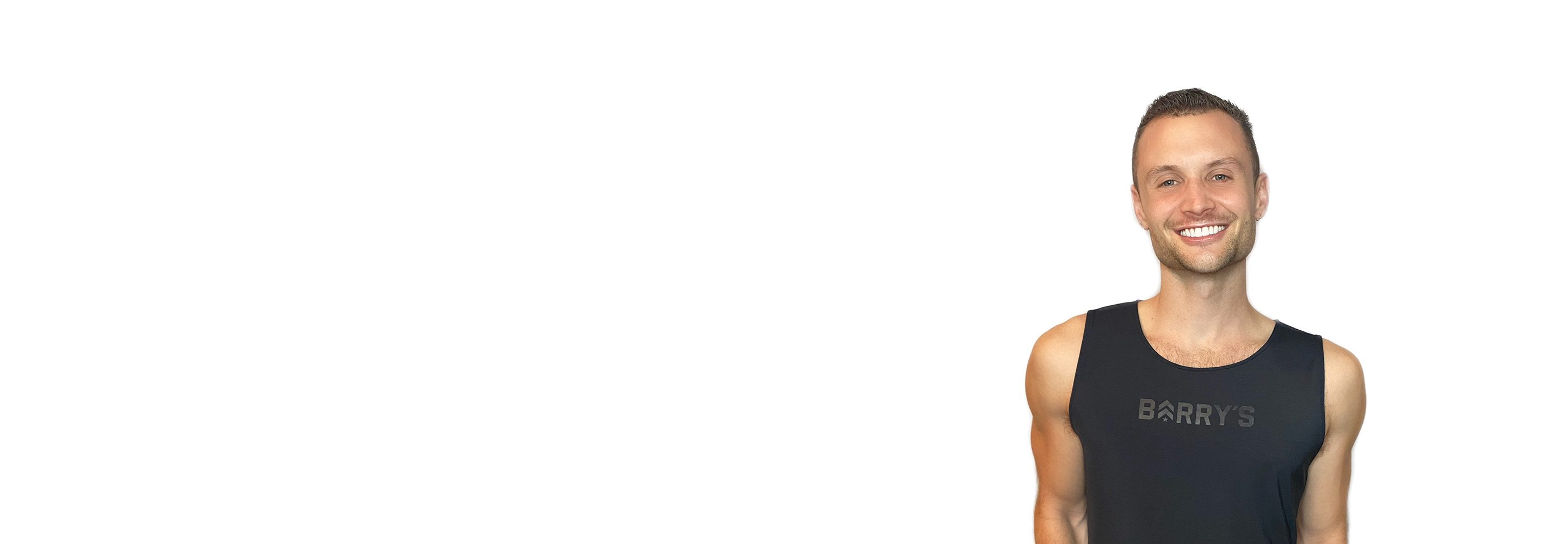 Barry’s instructor wearing a black top standing confidently smiling against a white background