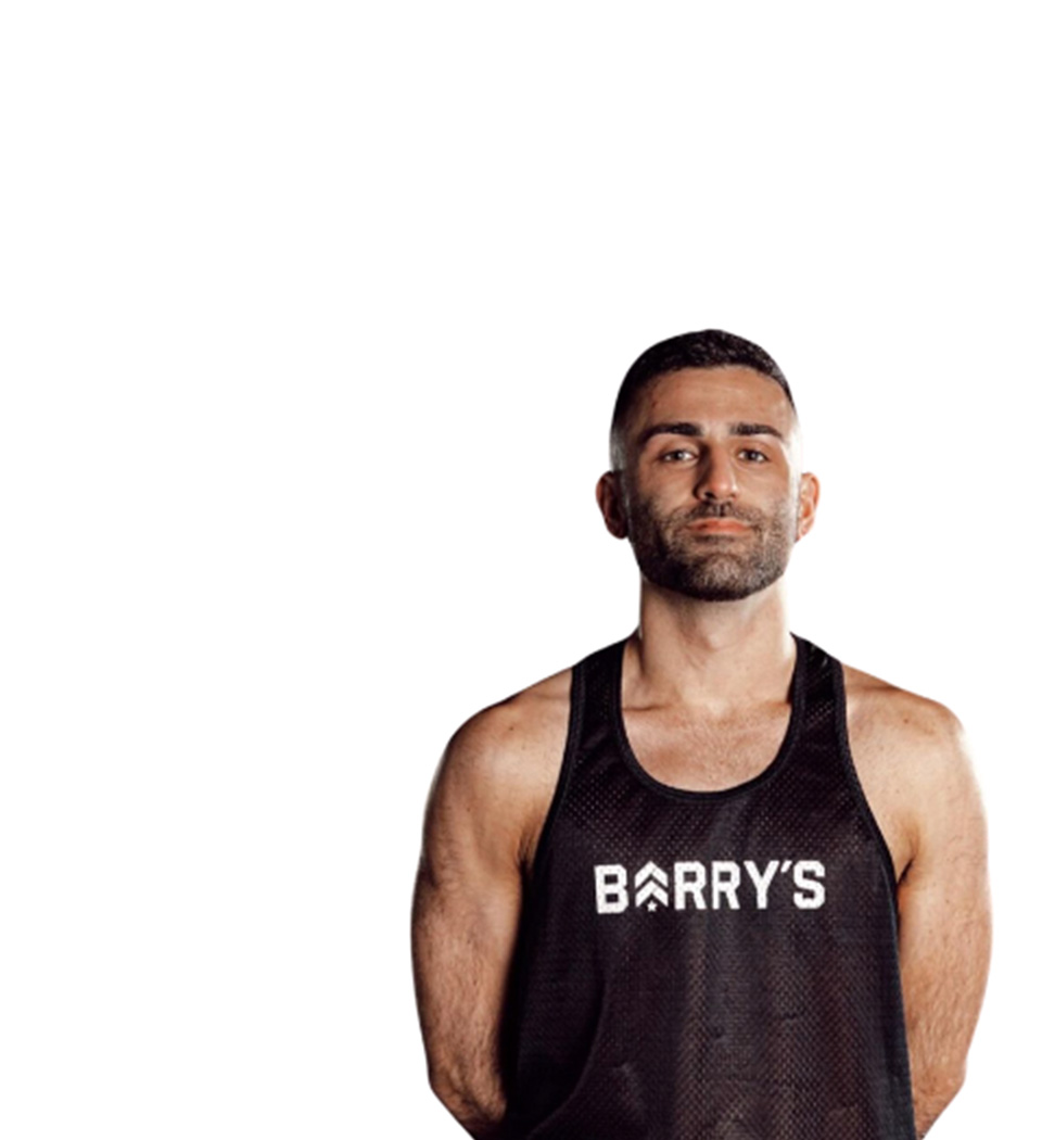 Barry’s instructor wearing a black top standing confidently smiling against a white background