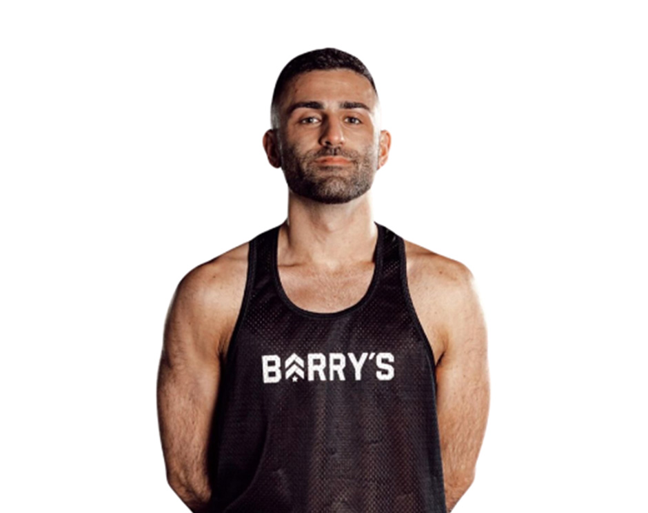 Barry’s instructor wearing a black top standing confidently smiling against a white background