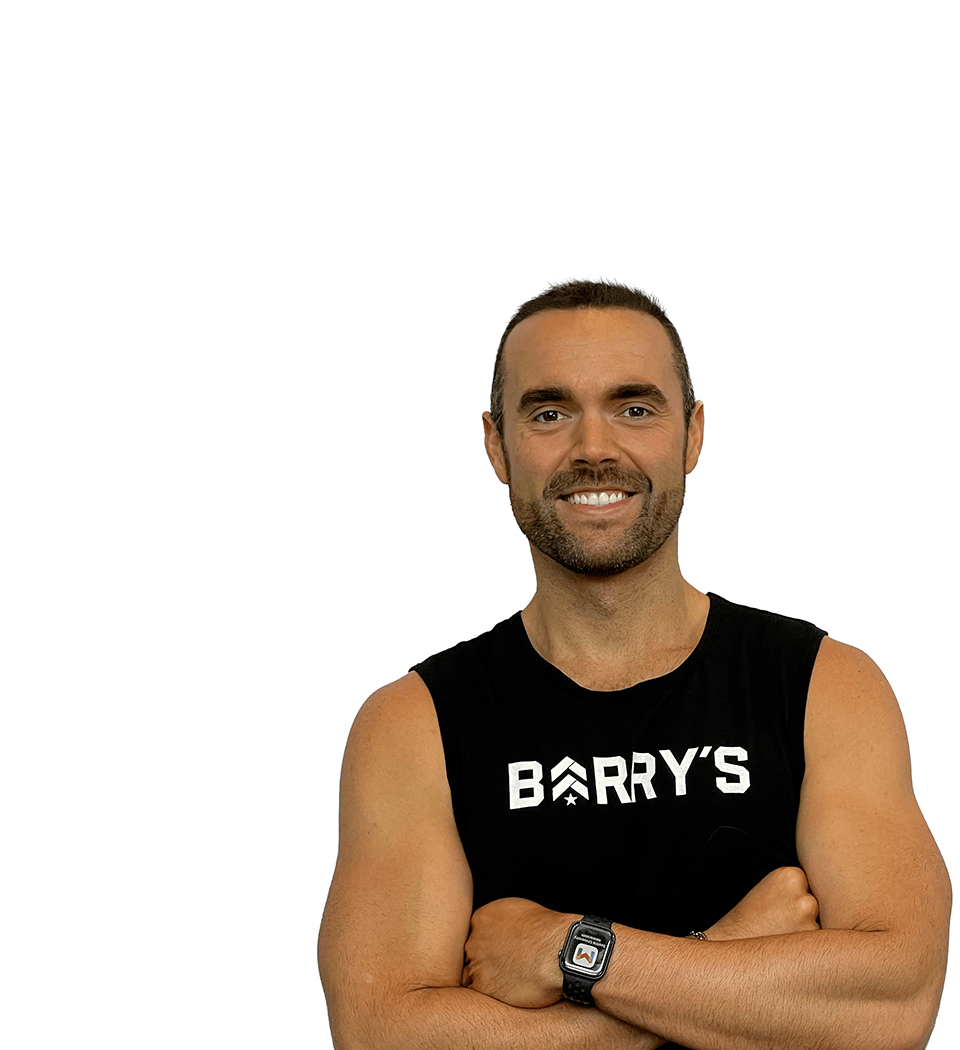Barry’s instructor wearing a black top standing confidently smiling against a white background