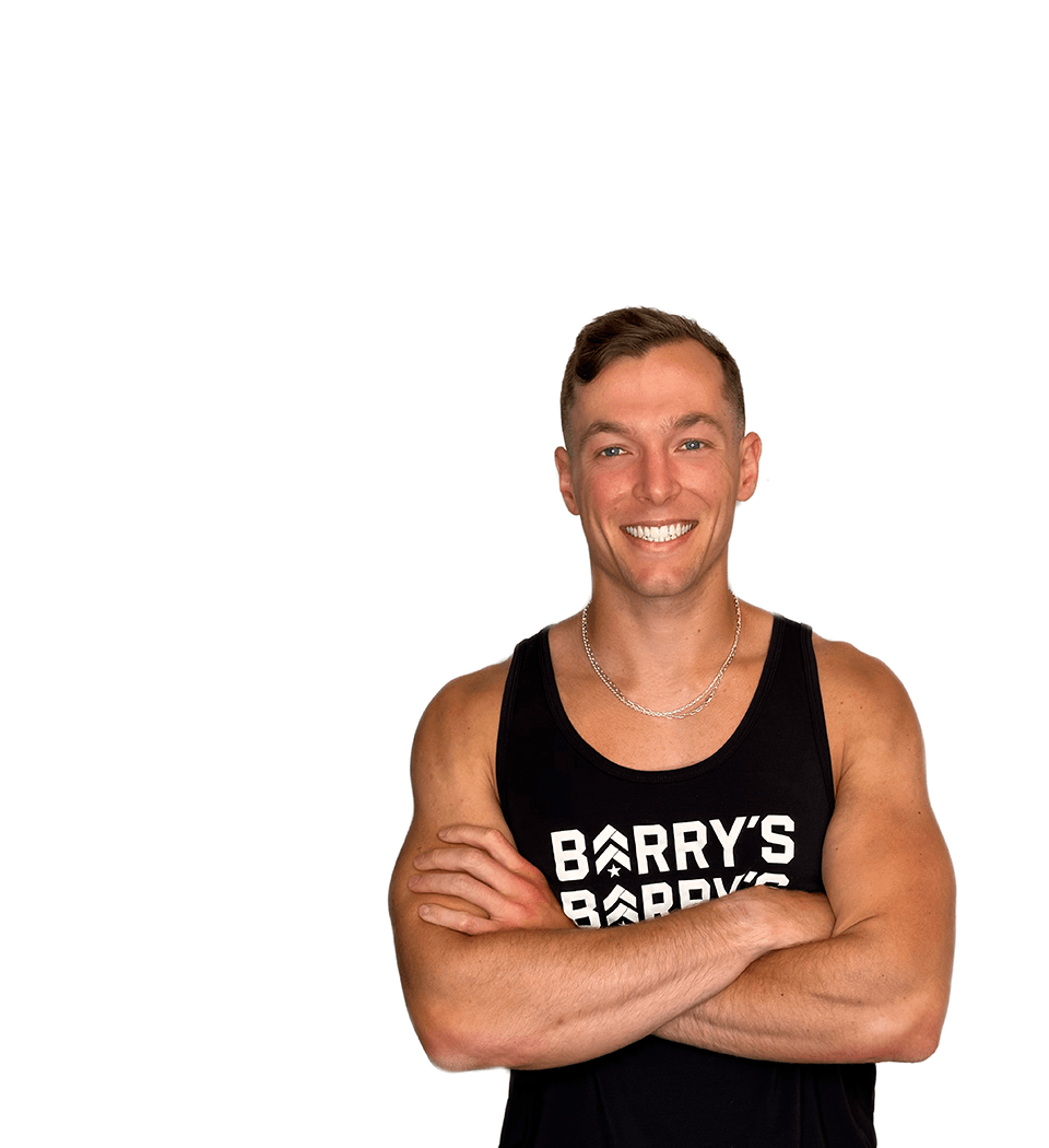 Barry’s instructor wearing a black top standing confidently smiling against a white background