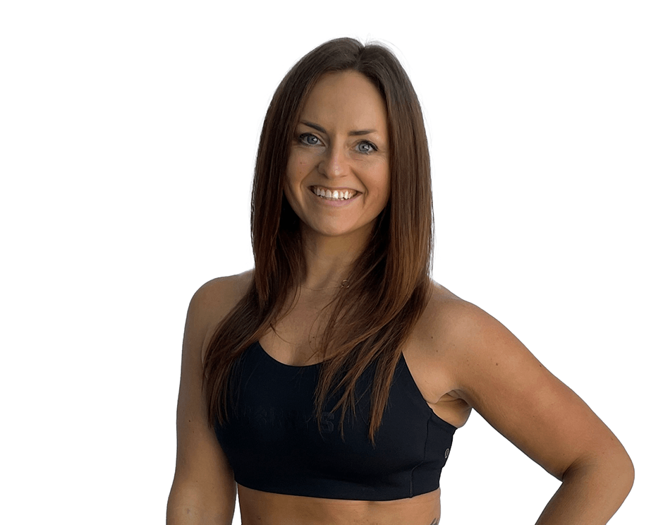 Barry’s instructor wearing a black top standing confidently smiling against a white background