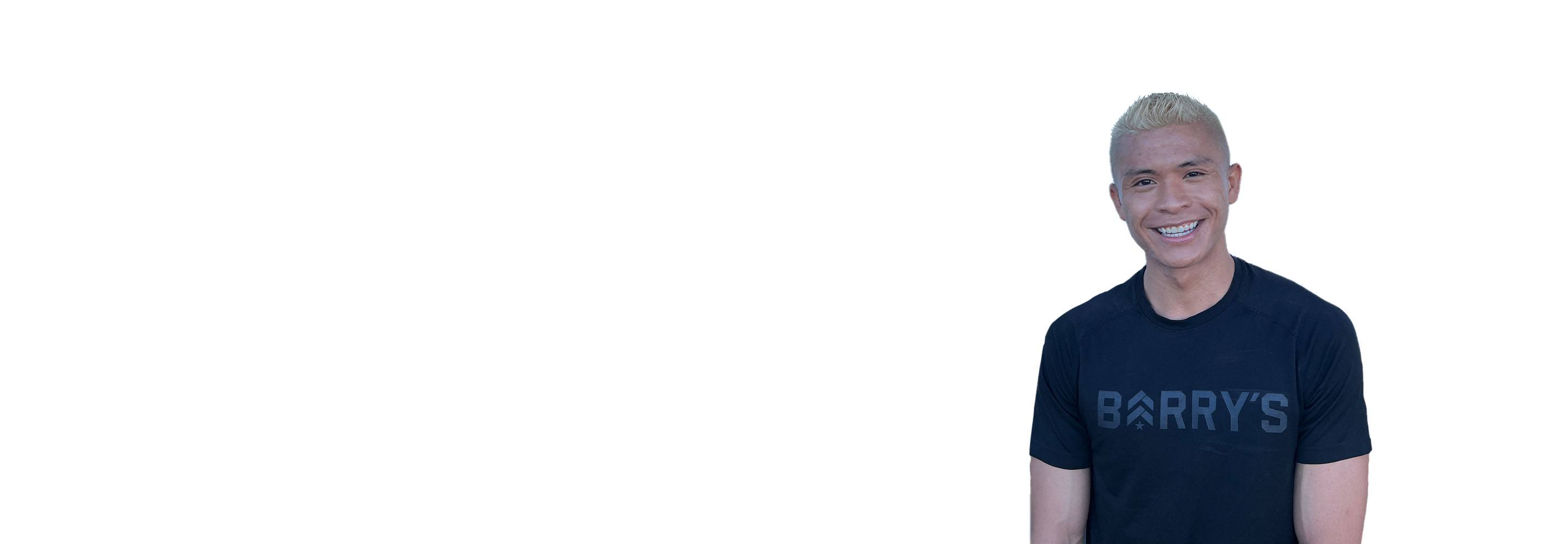 Barry's instructor standing confidently wearing a black top against a white background, ready for the next workout challenge.