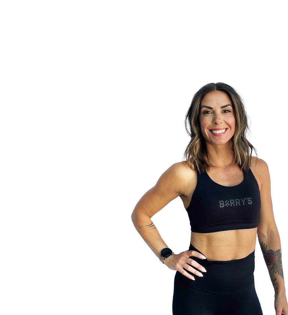 Barry’s instructor wearing a black top standing confidently smiling against a white background