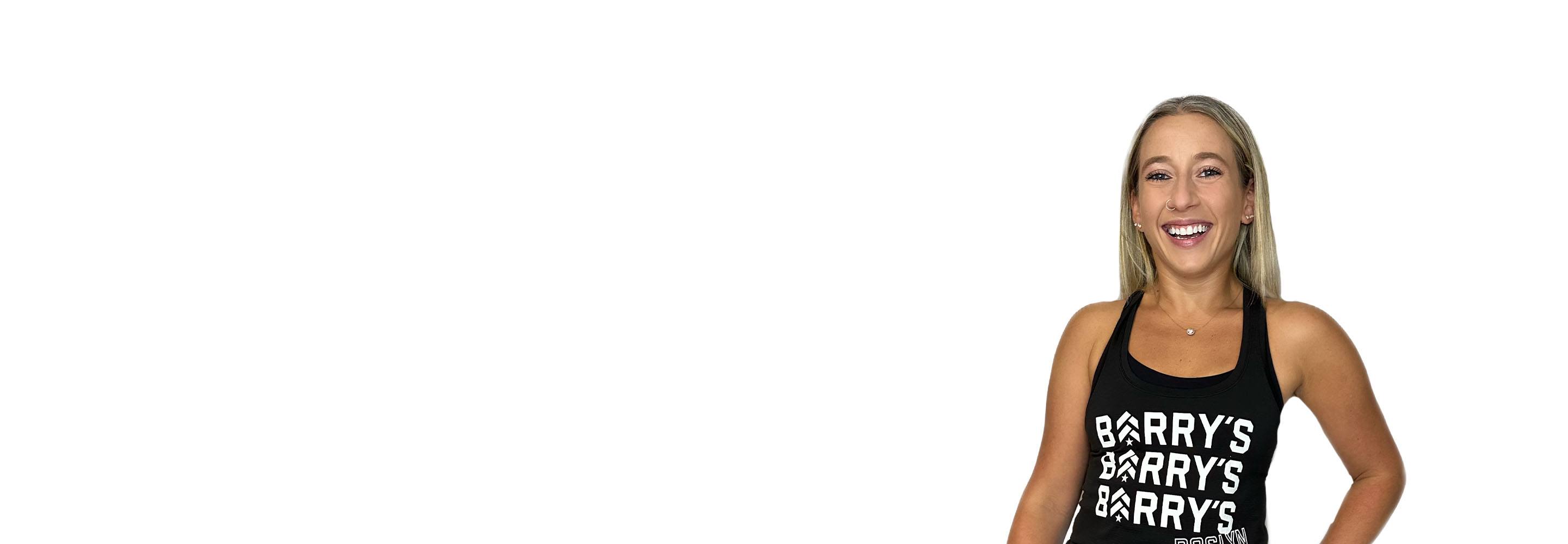 Barry’s instructor wearing a black top standing confidently smiling against a white background