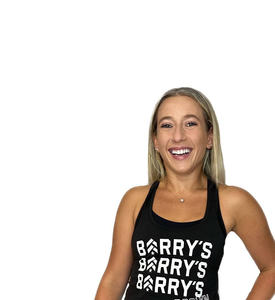 Barry’s instructor wearing a black top standing confidently smiling against a white background