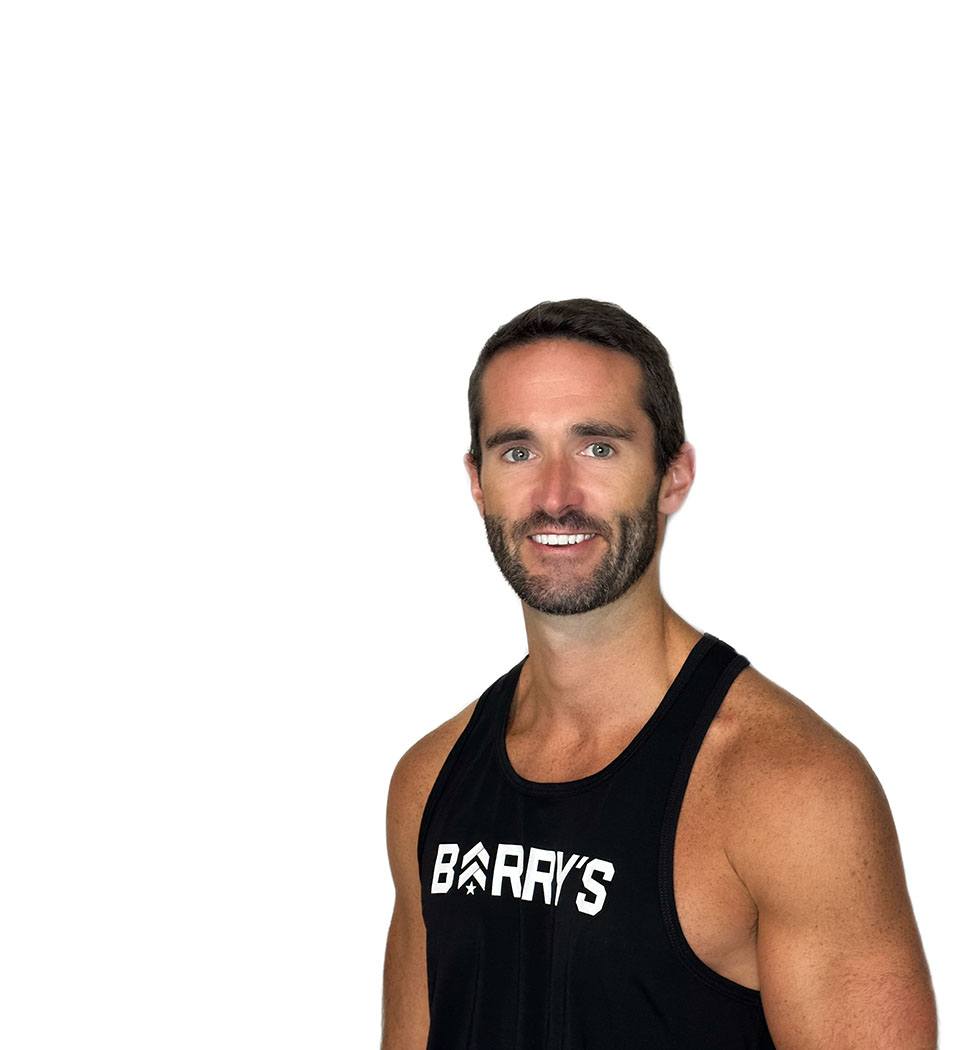 Barry’s instructor wearing a black top standing confidently smiling against a white background