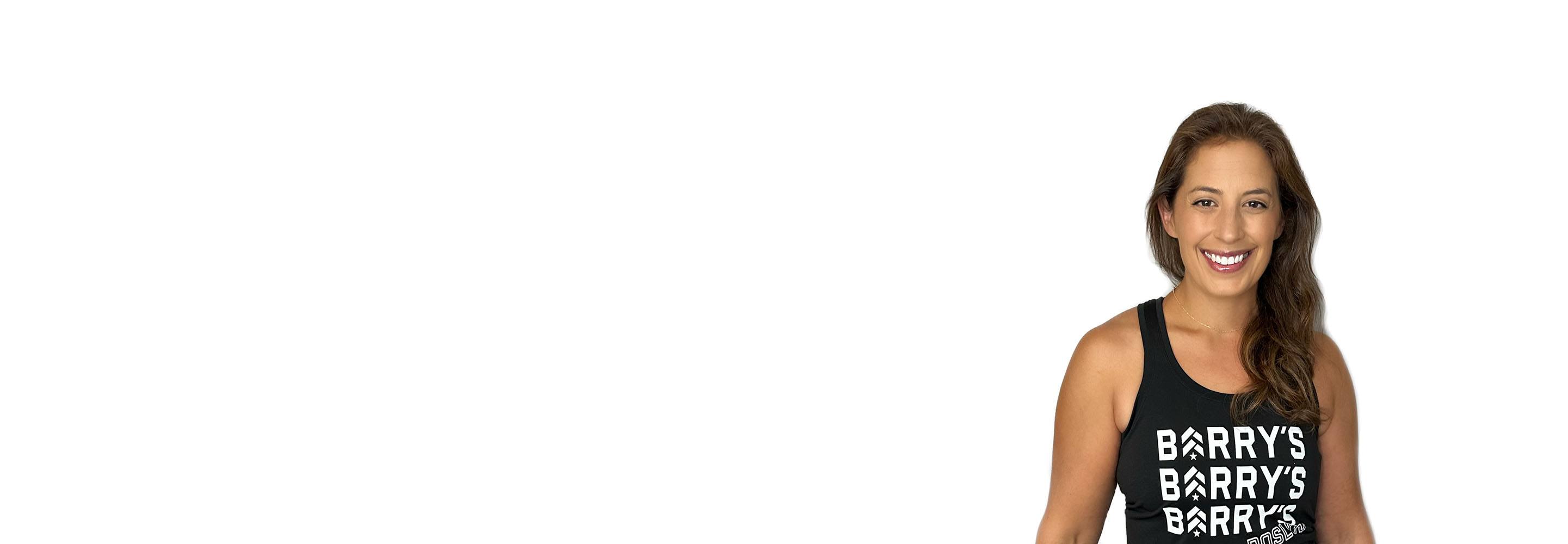 Barry’s instructor wearing a black top standing confidently smiling against a white background
