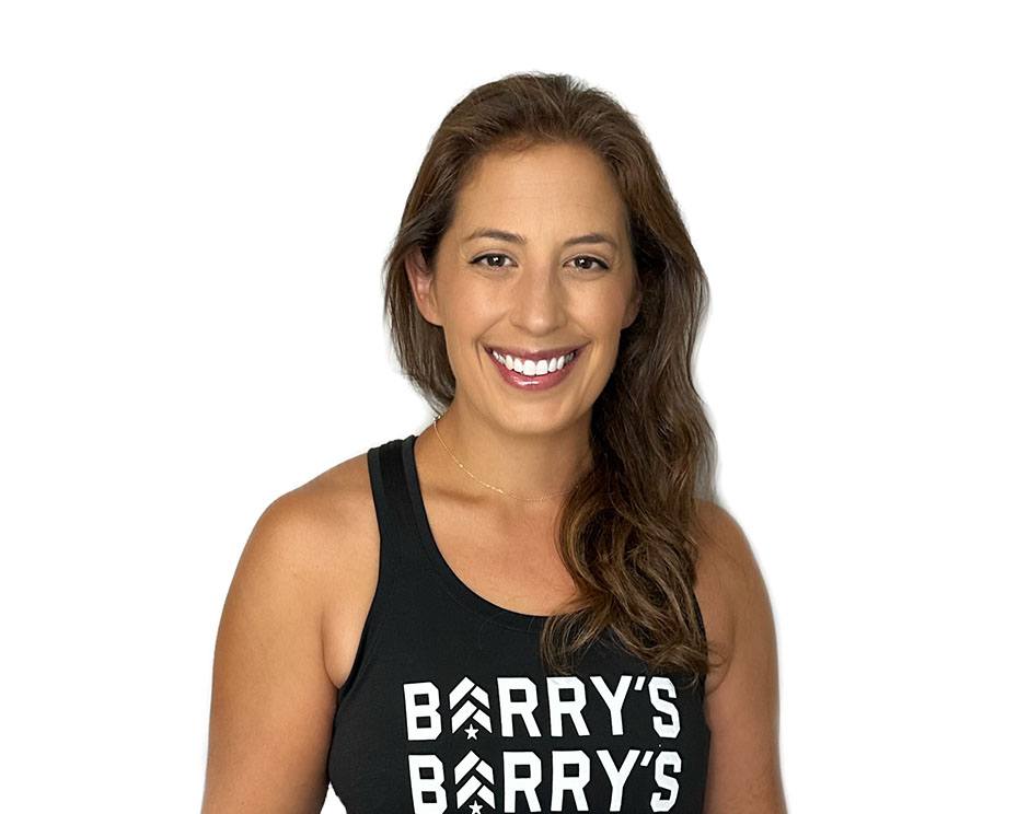 Barry’s instructor wearing a black top standing confidently smiling against a white background
